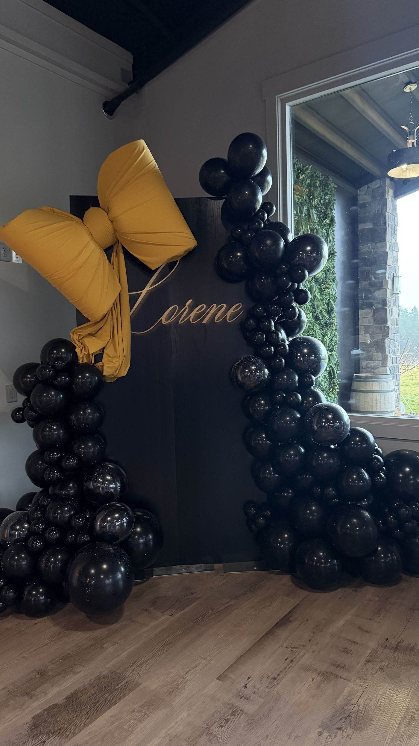 Custom name sign with black balloon garland and oversized mustard bow