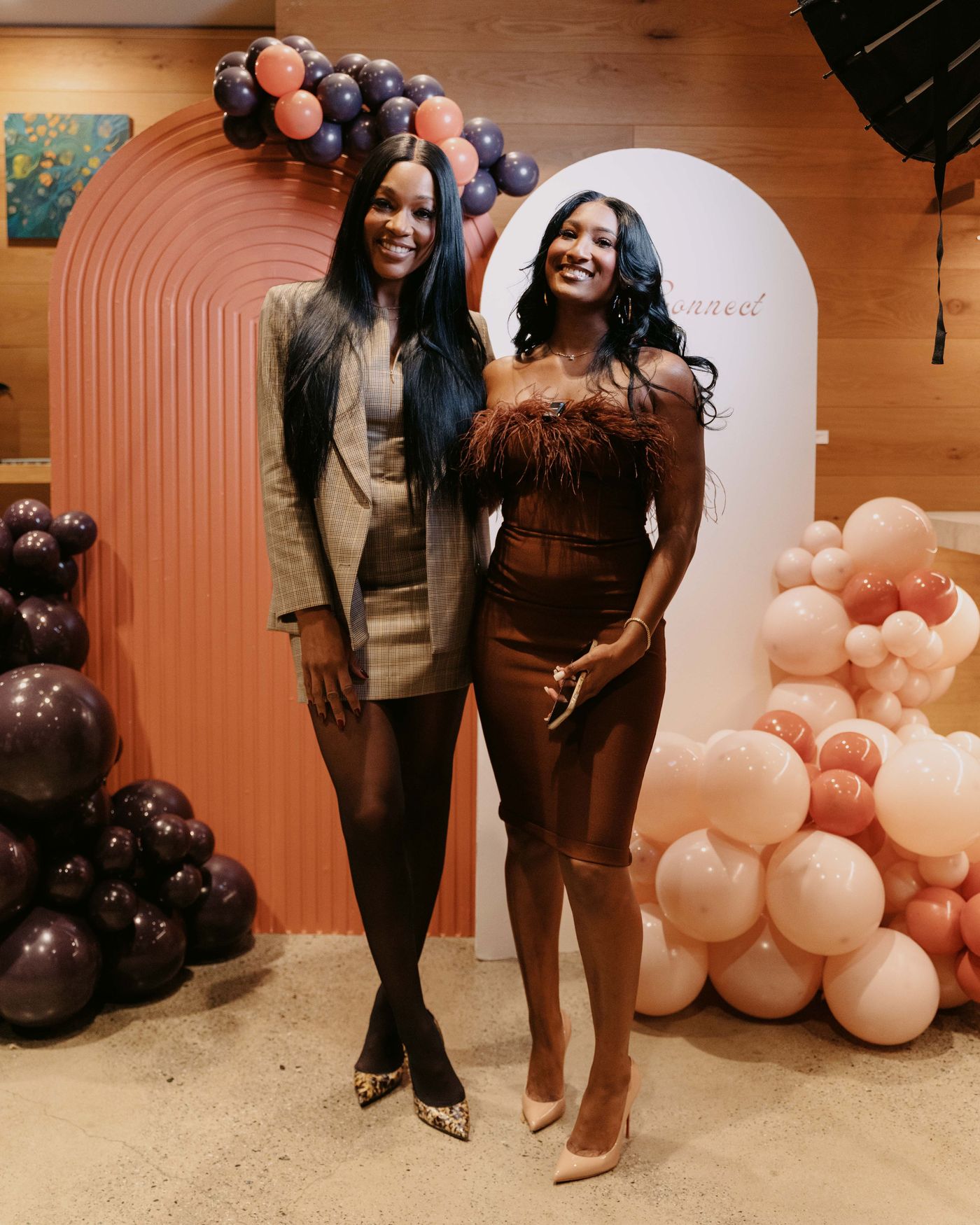 Two guests posing in front of custom arch and balloon garlands at The Color Connect